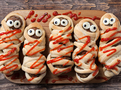 Hot dogs wrapped in crescent roll strips topped with ketchup and candy eyes